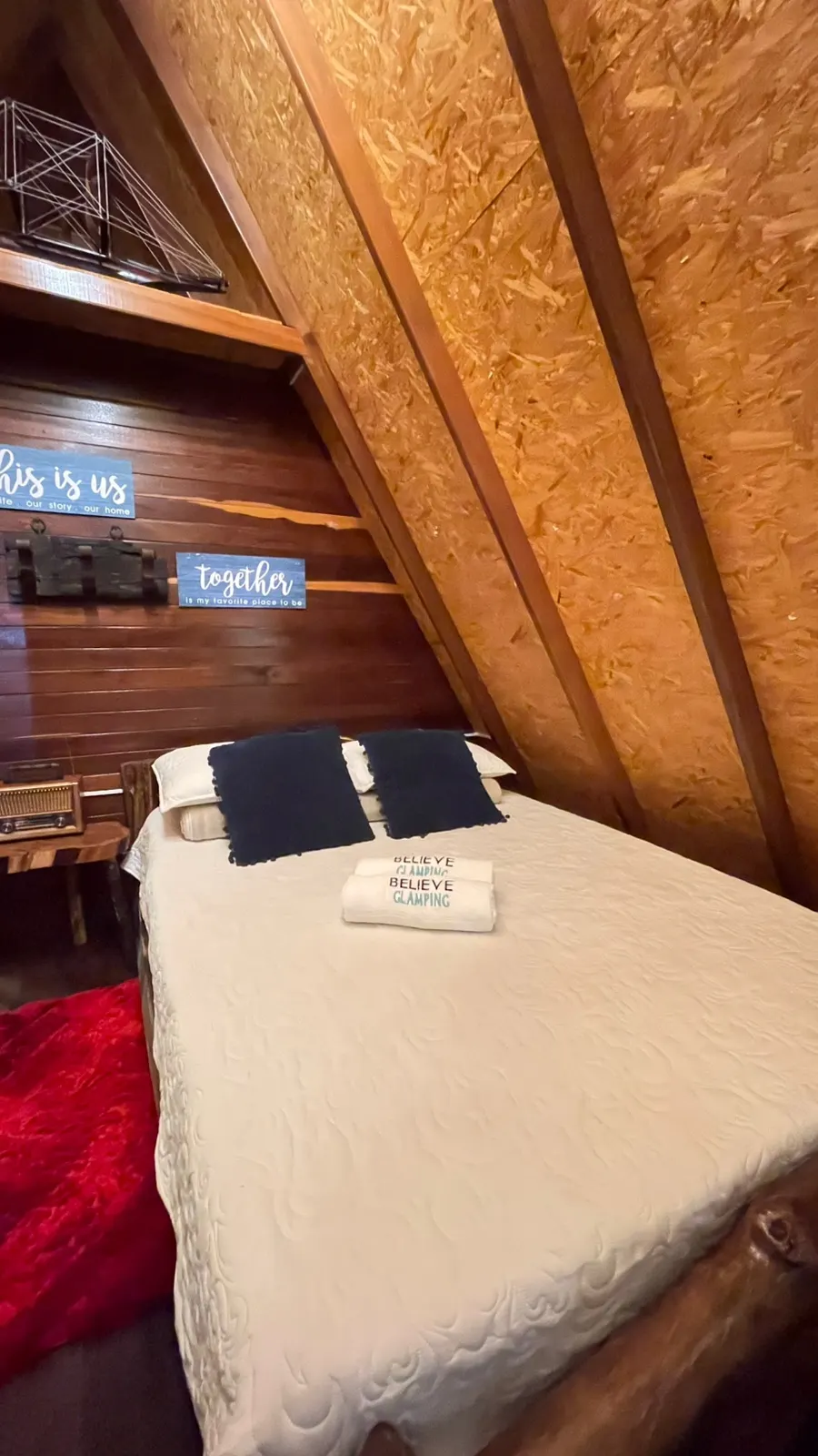 Cama doble con cojines y toallas en una cabaña de Belive Glamping